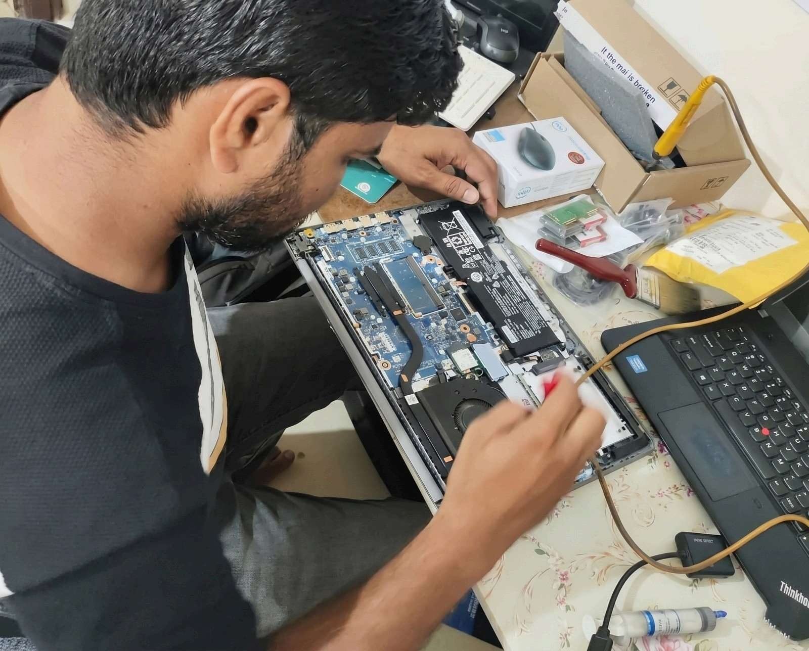 SwiftIT Solutions technician repairing a laptop motherboard
